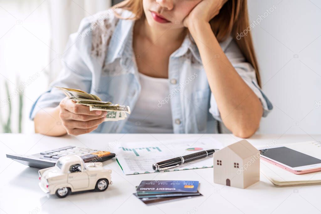 Stressed young woman calculating monthly home expenses, taxes, bank account balance and credit card bills payment, Income is not enough for expenses