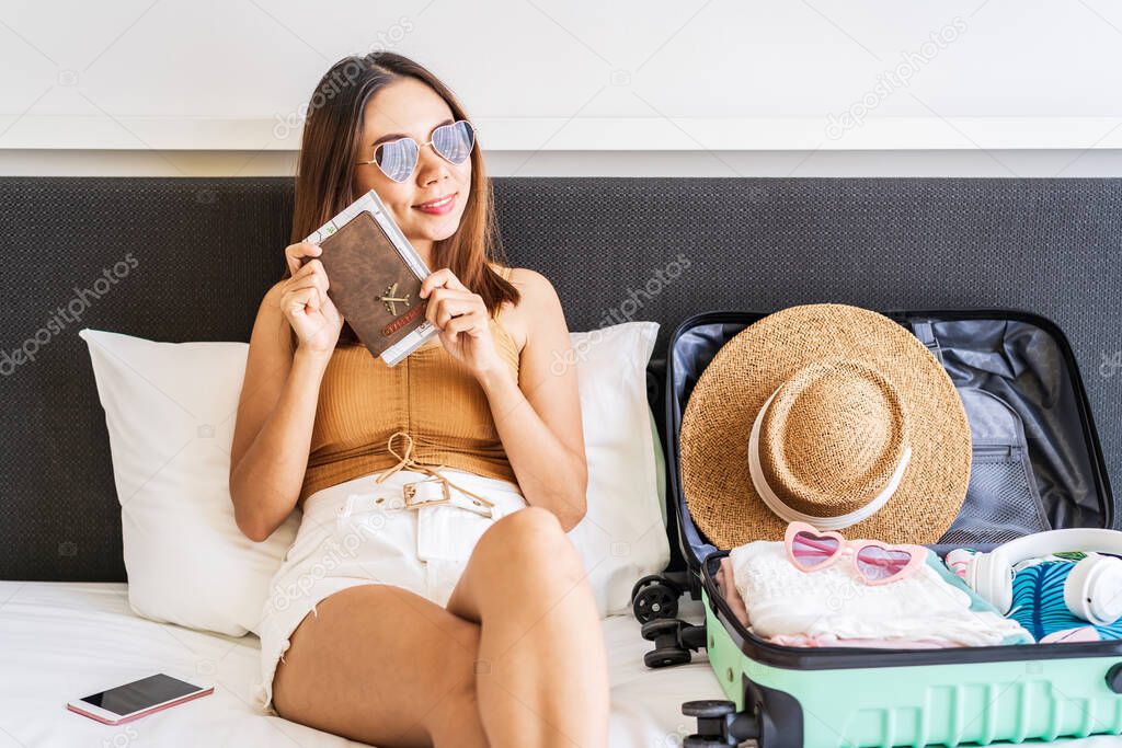 Young women traveler holding passport is happy to be able to travel and prepare luggage for summer vacation