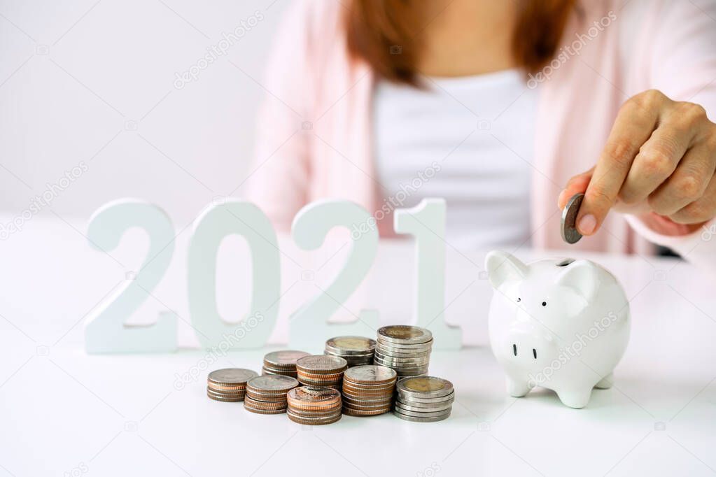 Stack of coins with young woman putting coin into the piggy bank, 2021 Saving money for future investment concept