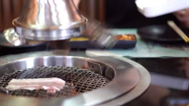 Kore barbeküsü yiyen genç bir kadın Yakiniku restoranında