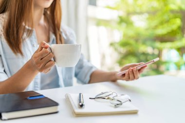 Genç bir kadın evde çalışırken kahve molası veriyor ve oturma odasında dinleniyor.