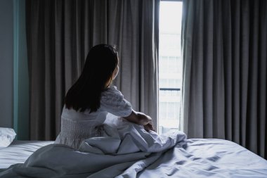 Yalnız genç bir kadın, karanlık bir odada otururken depresyonda ve stresli hissediyor, negatif duygular ve akıl sağlığı kavramı.