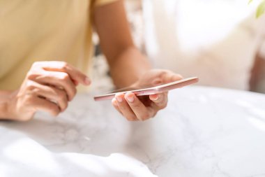 Gülümse mutlu Asyalı kadın rahatlıyor ve sabah evde akıllı telefon kullanıyor.