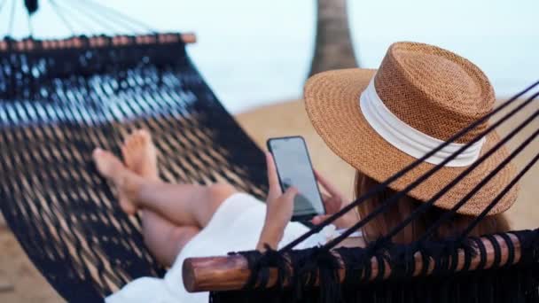 Junge Frau Liegt Auf Hängematte Und Benutzt Smartphone Strand Während — Stockvideo