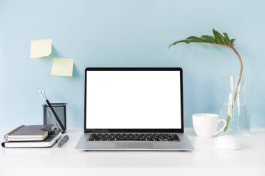 Modern ve şık çalışma alanı boş dizüstü bilgisayar ve masa başı ofis malzemeleriyle renkli arka plan ve kopyalama alanı oluşturur.