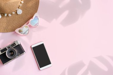 Boş ekran akıllı telefonlu aksesuar ögeleri ve fotokopi alanı ve yaz tatili kavramına sahip renk arkaplanı üzerinde retro kamera