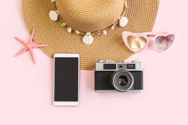 Boş ekran akıllı telefonlu aksesuar ögeleri ve fotokopi alanı ve yaz tatili kavramına sahip renk arkaplanı üzerinde retro kamera