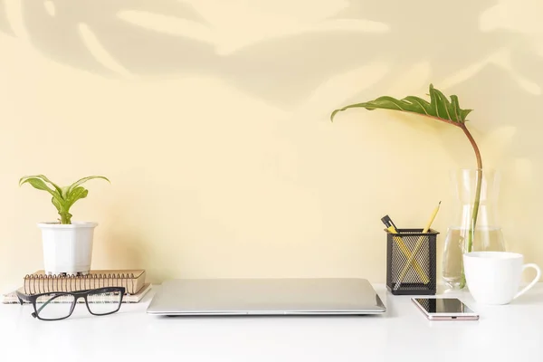 Modern and stylish workspace mock up with laptop and desk office supplies with color background and copy space