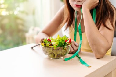 Genç kadın evde taze sebze yerken sıkılıyor, sağlıklı besleniyor yaşam tarzı ve diyet kavramı