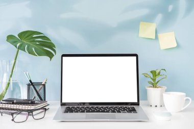 Modern ve şık çalışma alanı boş dizüstü bilgisayar ve masa başı ofis malzemeleriyle renkli arka plan ve kopyalama alanı oluşturur.