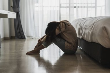 Yalnız genç bir kadın, karanlık bir odada otururken depresyonda ve stresli hissediyor, negatif duygular ve akıl sağlığı kavramı.