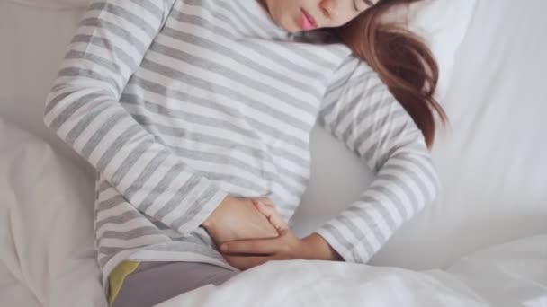 若い女性がベッドで腹痛を起こしている 期間けいれんの問題の概念 — ストック動画