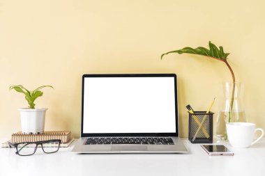 Modern ve şık çalışma alanı boş dizüstü bilgisayar ve masa başı ofis malzemeleriyle renkli arka plan ve kopyalama alanı oluşturur.