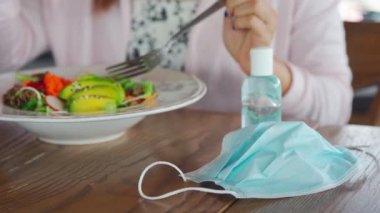 Restoranda yemekten önce Corona virüsü ve bakterisi bulaşmasın diye alkol jeli dezenfektanı kullanan genç bir kadın. Yeni normal yaşam tarzı kavramı.
