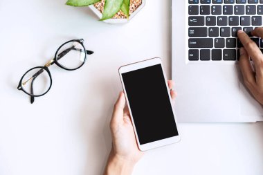 Boş ekranı tutan akıllı telefon fotokopi alanı ve üst görünümü olan ofis masasında.