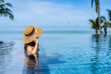 Genç bayan gezgin yaz tatili ve seyahat konsepti için seyahat ederken tropik bir tatil havuzu kenarında dinleniyor ve eğleniyor.