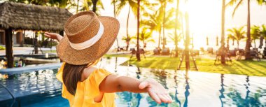 Genç bayan gezgin yaz tatili için seyahat ederken tropik bir tatil havuzu kenarında gün batımının tadını çıkarıyor.