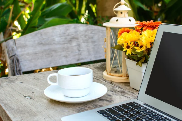 Coffee, laptop on wooden table with flower