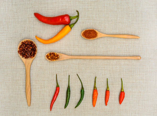 Chili y pimentón con cuchara de madera sobre saco —  Fotos de Stock