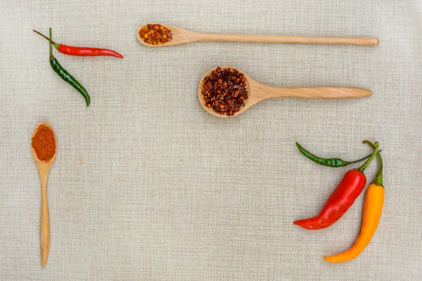 Chili y pimentón con cuchara de madera sobre saco —  Fotos de Stock