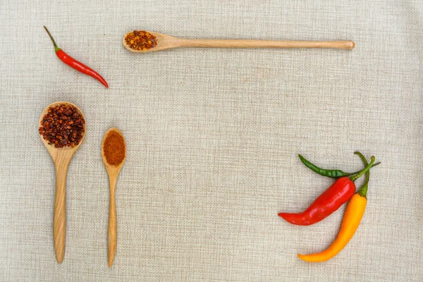 Chili y pimentón con cuchara de madera sobre saco —  Fotos de Stock