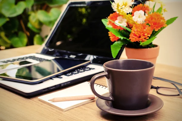 Portátil y taza de café con flores en el escritorio — Foto de Stock