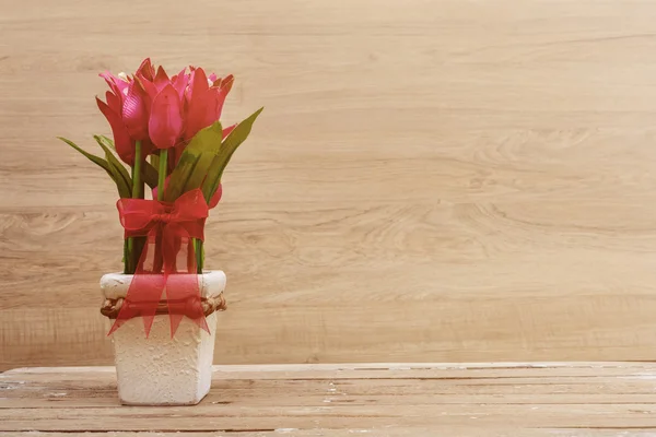 Fiori e pentola su vecchio tavolo di legno — Foto Stock