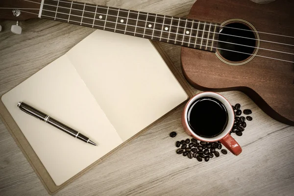Ceașcă de cafea cu ukulele și notebook pe masă de lemn — Fotografie, imagine de stoc