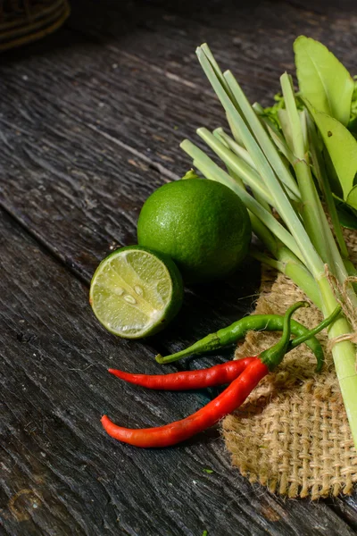 Chili pepper with lime and Kaffir lime leaf on old wooden table Stock Photo