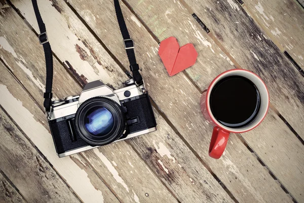 Taza de café con cámara retro en mesa de madera vieja —  Fotos de Stock