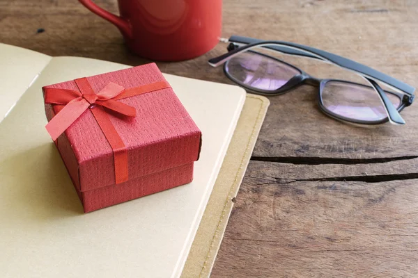 Rote Geschenkbox mit Notizbuch und Tasse Kaffee — Stockfoto