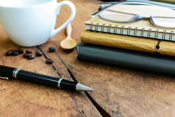 Nahaufnahme von Stift mit Notizbuch und Tasse Kaffee auf Holztisch — Stockfoto
