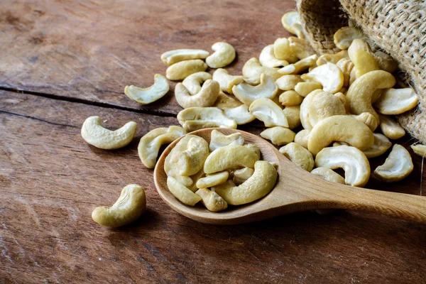 Cashew nuts with wooden spoon on old wood textured — Stock Photo, Image