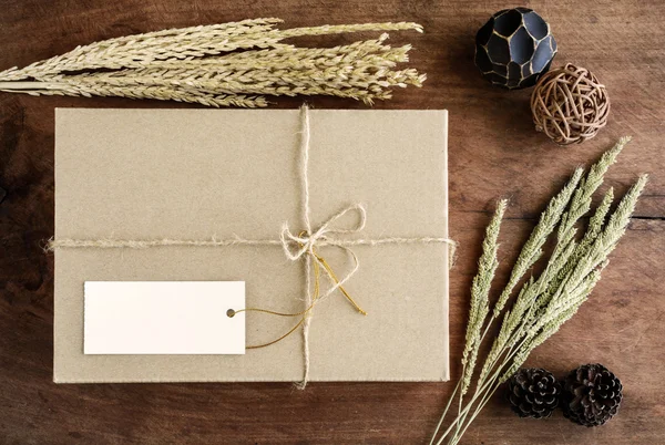 Brązowy papier pudełko na stare drewniane tła z suszonych kwiatów — Zdjęcie stockowe