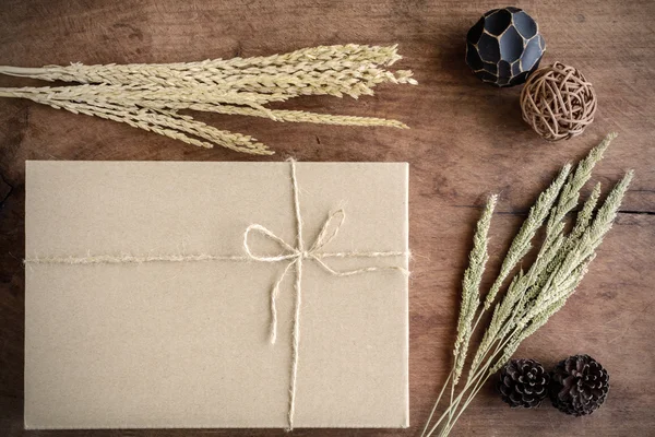 Braune Papierschachtel auf altem Holzhintergrund mit getrockneter Blume — Stockfoto