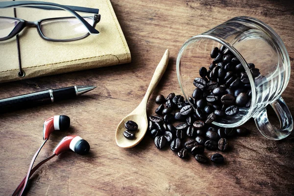 Taza con grano de café y cuaderno en mesa de madera vieja —  Fotos de Stock