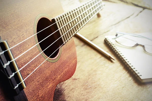 Close up de ukulele no fundo de madeira velha com luz macia — Fotografia de Stock