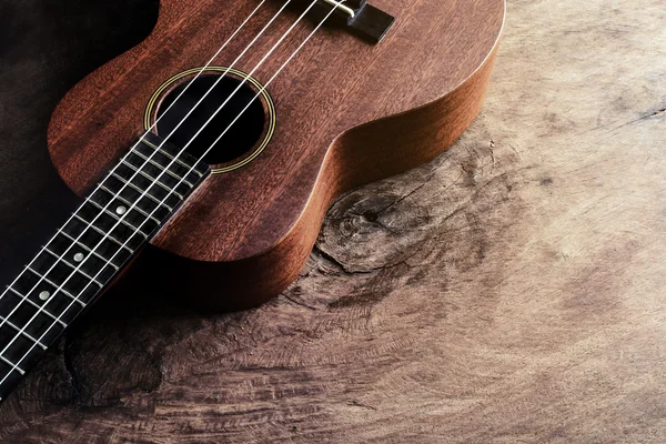 Close up de ukulele no fundo de madeira velha com luz macia — Fotografia de Stock