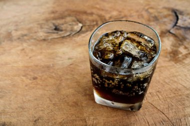 A glass of cola with ice on old wood