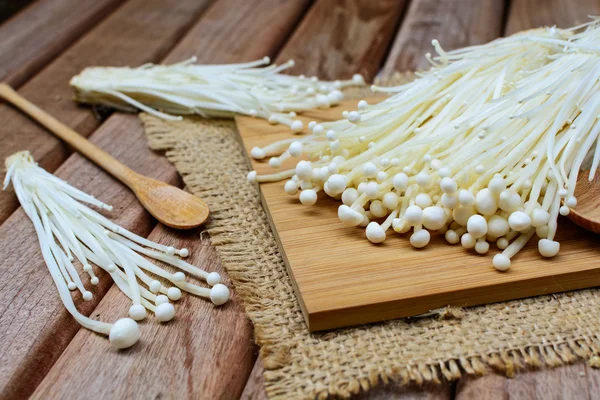 Ahşap masa üzerinde kaşıkla enoki mantar