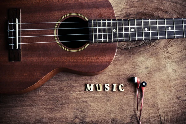 Close up de ukulele e fone de ouvido no fundo de madeira velha — Fotografia de Stock