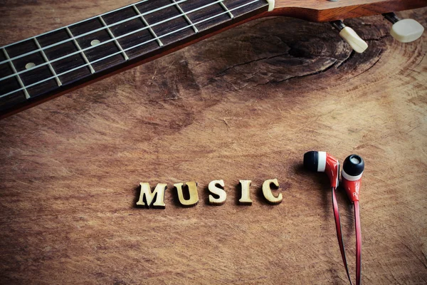 Close up de ukulele e fone de ouvido no fundo de madeira velha — Fotografia de Stock