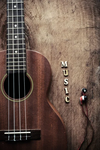 Close up de ukulele e fone de ouvido no fundo de madeira velha — Fotografia de Stock