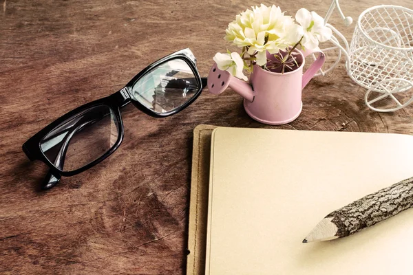 Open blank notebook with flower and glasses on wooden table — Stock Photo, Image