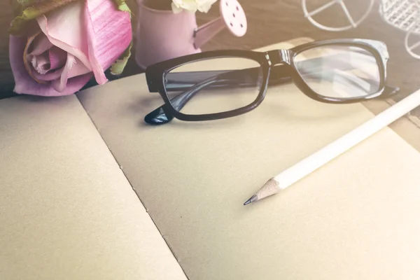打开空白笔记本以花和木制的桌子上的眼镜 — 图库照片