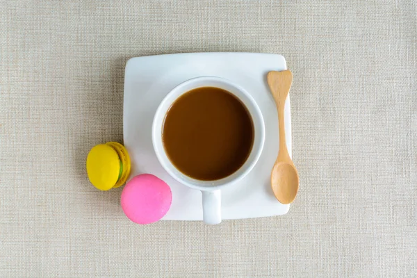 Macarrones coloridos y una taza de café con cuchara de madera —  Fotos de Stock