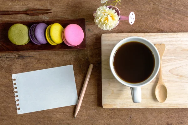 Macarrones coloridos con café y nota en blanco en la mesa de madera — Foto de Stock