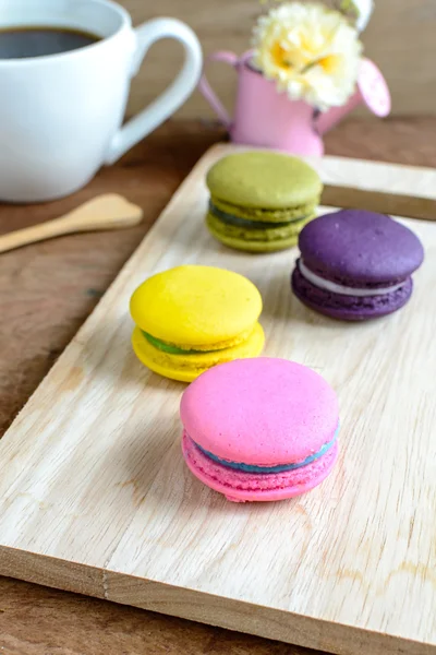 Macarrones coloridos y una taza de café sobre una mesa de madera —  Fotos de Stock