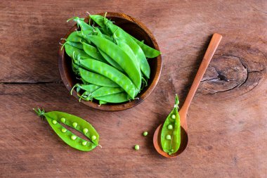 ahşap masa üzerinde yeşil bezelye genç taze bakla