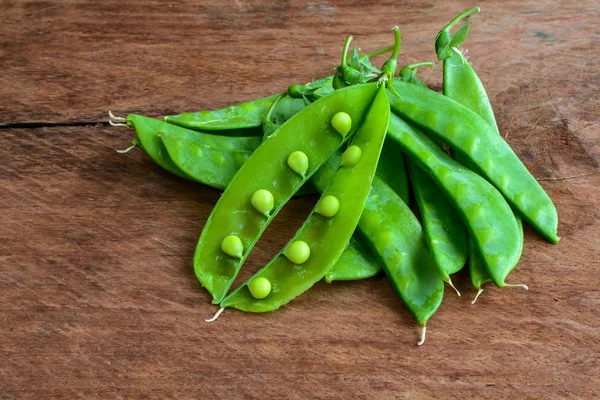 Ung fräsch baljor av gröna ärtor på träbord — Stockfoto